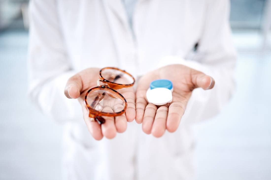 The image shows hands in a medical coat holding glasses and contacts to show whether contacts, glasses, or LASIK is best.